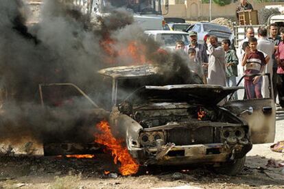 Varios viandantes observan los restos humeantes de un coche civil atacado con una bomba en la ciudad de Mosul, 400 kilómetros al norte de Bagdad.