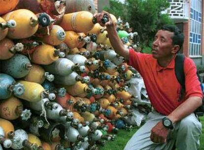 Imagen de 2001 del escalador Appa Sherpa inspeccionando varias botellas de oxígeno vacías traídas de la montaña más alta del mundo, en Katmandú ( Nepal)