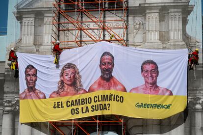 Activistas de Greenpeace descuelgan la lona en la Puerta de Alcalá de Madrid. 