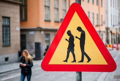 TOPSHOT - A road sign arning against pedestrians focusing on their smartphones is pictured on February 2, 2016 near the old town in Stockholm. / AFP / JONATHAN NACKSTRAND