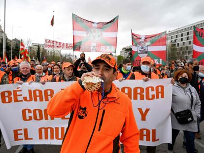 A man blows in a conch shell horn as demonstrators hold a banner and wave "Ikurrina" Basque flags during a demonstration called by farmers trade unions and hunting federations, forming a "Rural Alliance", to mark the economic and social importance of the rural sector and to demand "a future for the countryside", in Madrid on March 20, 2022. (Photo by Pierre-Philippe MARCOU / AFP)