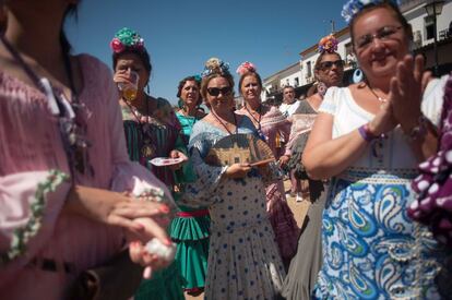Un grupo de mujeres vestidas de flamencas festejan la procesión de la Virgen del Rocío.