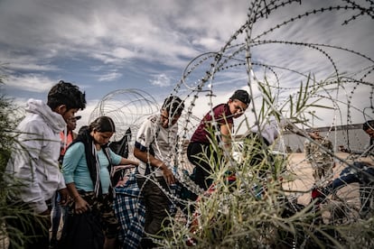 Migrantes venezolanos cruzan el alambrado colocado por la patrulla fronteriza de El Paso, Texas, desde Ciudad Juárez, en octubre de 2023.