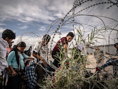 Migrantes venezolanos cruzan el alambrado colocado por la patrulla fronteriza de El Paso, Texas, desde Ciudad Juárez, en octubre de 2023.