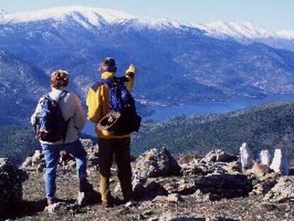 Dos personas otean desde el Cerro Merina las cumbres de Gredos y el embalse del Burguillo.