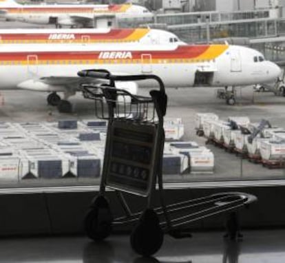 Un carrito de equipajes ante varios aviones de Iberia, ayer en la T4 del aeropuerto de Barajas.