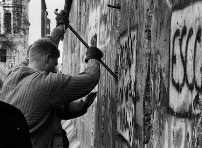 Un hombre utiliza una barra de hierro para contribuir al derribo del muro de Berlín. La gente utilizaba picos y martillos para destruir las paredes que durante 28 años dividieron Berlín en dos, mientras excavadoras y grúas destruían el Muro sección por sección.