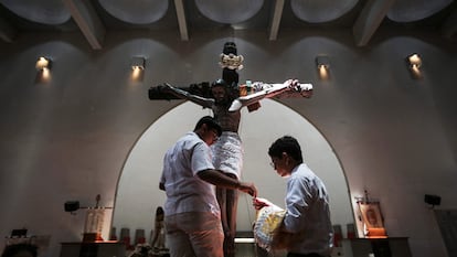 Two young men fix a statue of Jesus Christ after a procession in Managua, on April 7, 2023.