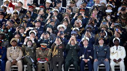 Oficiales de alto rango de varios paises usan sus teléfonos para grabar y tomar fotografías durante el tradiconal desfile militar celebrado con motivo del día de la fiesta nacional francesa en París (Francia).