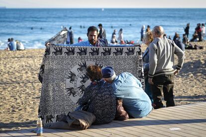 Una parella observa el material d'un venedor ambulant a la platja de Barcelona.