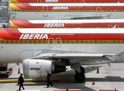Dos pilotos, junto a aviones de Iberia estacionados en el aeropuerto de Barajas.
