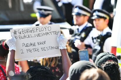 Manifestante segura cartaz durante protesto contra o assassinato de George Floyd em frente à embaixada dos EUA em Londres, neste domingo.