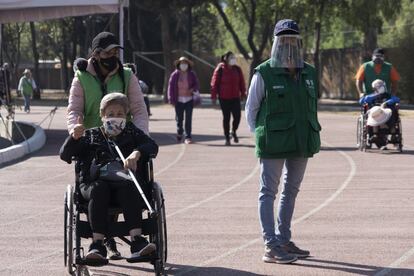 Una persona mayor es ayudada a pasear por quien la cuida.