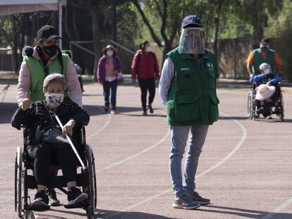 Una persona mayor es ayudada a pasear por quien la cuida.