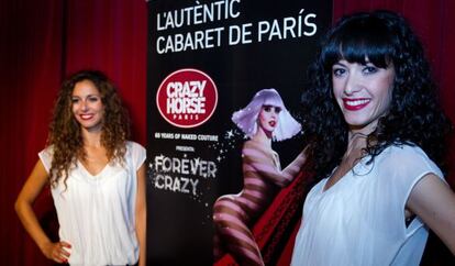 Dos de las bailarinas del cabaré parisino Crazy Horse, ayer en Barcelona junto al cartel anunciador del espectáculo.