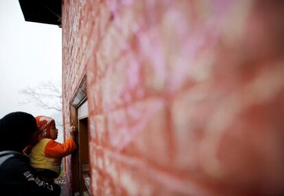 Un padre ayuda a su hijo a escribir con tiza en una pared, durante el festival Shreepanchami, en el templo Saraswati en Katmandú (Nepal), el 1 de febrero de 2017.