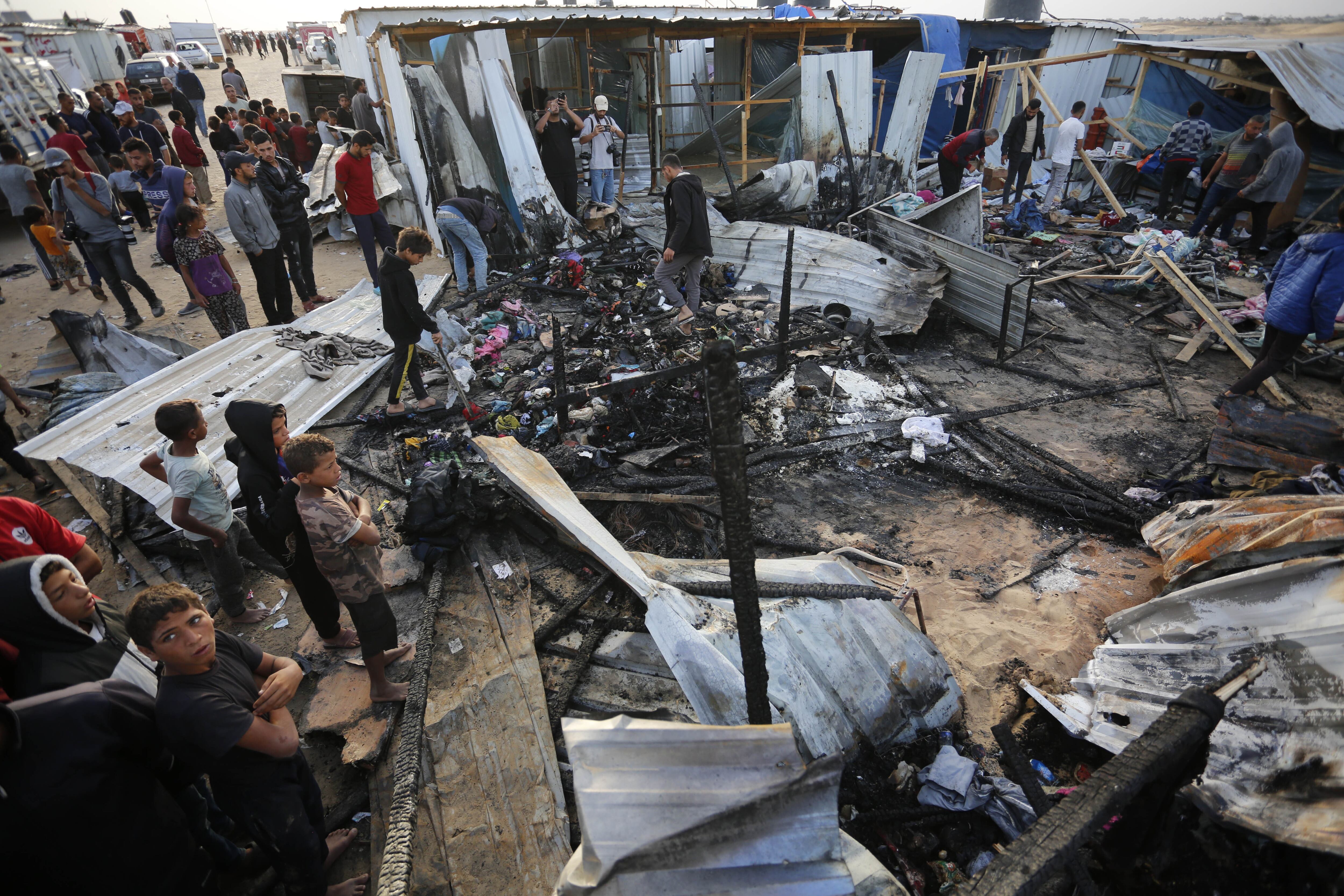 Decenas de personas observan la destrucción causada por un bombardeo del ejército israelí contra un campo de refugiados  en Rafah, este lunes. 
