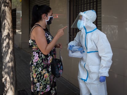 Una mujer habla con una sanitaria en Ripollet (Barcelona), donde la Generalitat comenzó este miércoles un cribado masivo y voluntario para detectar positivos.