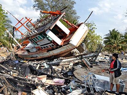 Nataya Pumsi, de 36 años, contempla los restos de su casa, reducida a escombros, y de un barco arrastrado por el <i>tsunami</i>, en Ban Nam Khem (Tailandia)
.