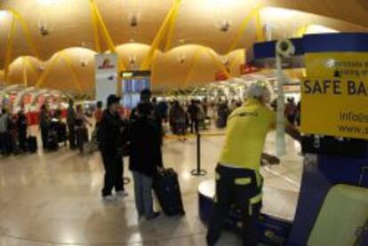 Decenas de personas guardan su turno para facturar las maletas en la T4 del Aeropuerto de Barajas.