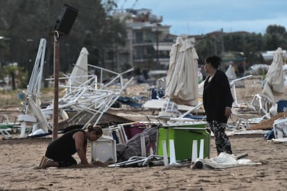 Mulheres buscam pertences em meio aos escombros de um quiosque destruído na praia de Nea Plagia.