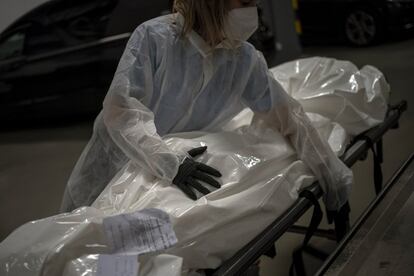 Marina Gómez, empleada de una funeraria, maneja el cadáver de una víctima del coronavirus en la morgue de su empresa, Mémora, en Barcelona.