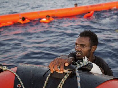 Un migrante eritreo se agarra a un bote salvavidas despu&eacute;s de haber saltado al agua desde una patera durante esta operaci&oacute;n de rescate, a 13 kil&oacute;metros al norte de Sabratha (Libia). 