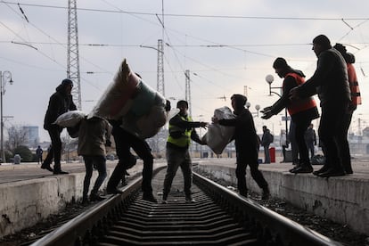 Voluntarios transportan sobre las vías del tren ayuda médica y artículos de primera necesidad en la estación de tren de Lviv, en el oeste de Ucrania.