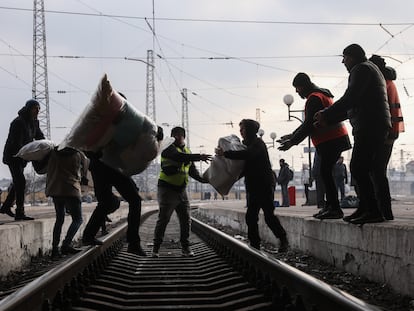 Voluntarios transportan sobre las vías del tren ayuda médica y artículos de primera necesidad en la estación de tren de Lviv, en el oeste de Ucrania.