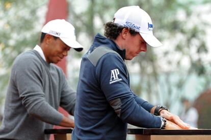 Tiger y McIlroy firman con sus manos.