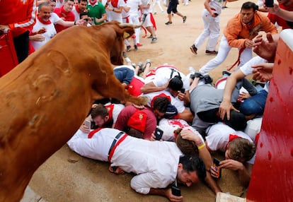 Varios corredores graban con sus móviles desde el suelo mientras un toro les salta por encima a la entrada de la plaza.