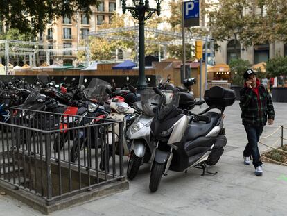 Un hombre camina entre motos y un alcorque, en la plaza de la Catedral de Barcelona, este viernes.