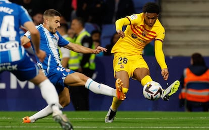 El jugador del FC Barcelona Alex Balde centra ante la oposición de dos jugadores del Espanyol.  