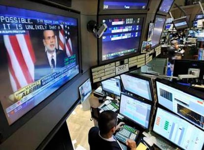Una pantalla de televisión en la sala de operaciones de la Bolsa de Nueva York muestra la intervención de Ben Bernanke.