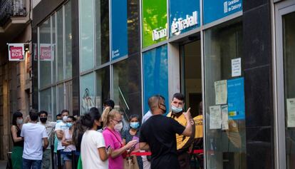 Personas con mascarilla, hacen cola en la Oficina de Treball de la Generalitat 