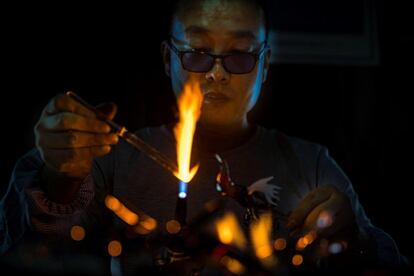 Un trabajador moldea una pieza decorativa de cristal en un taller tradicional en Zibo, en la provincia de Shandong (China). 