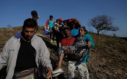 Un hombre ayuda a la octogenaria Aura Soto a cruzar de Venezuela a Brasil en la frontera en Pacaraima.