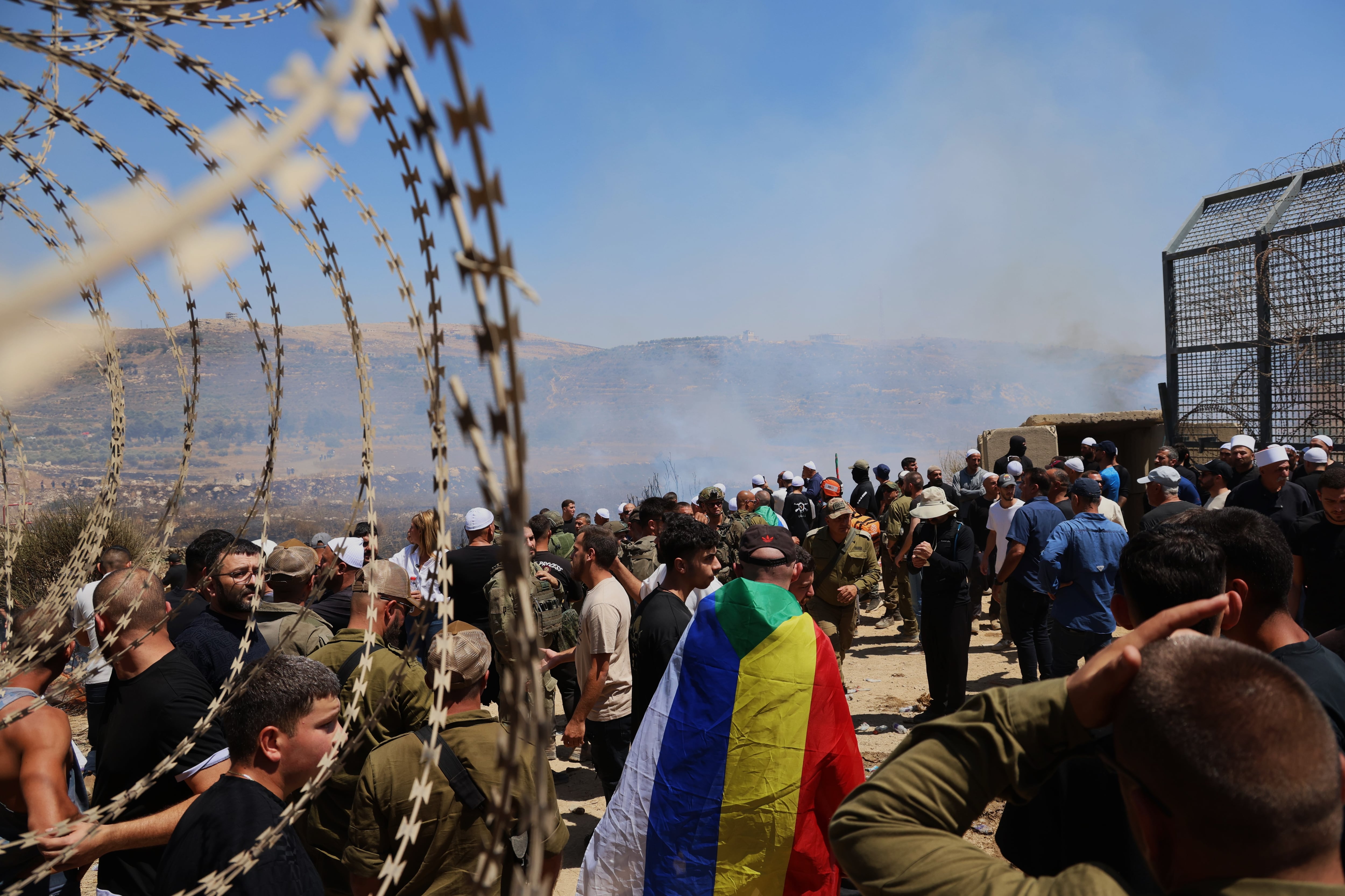 Cientos de personas pasan de uno a otro lado de la valla de los Altos del Golán sirios después de ser abierta por tropas israelíes.