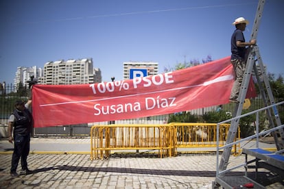 Dos operarios colocan una pancarta de Susana Díaz en el Muelle de las Delicias (Sevilla).
