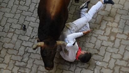 A participant is struck by a bull during the "encierro" (bull-run) of the San Fermin festival in Pamplona, northern Spain on July 12, 2022. - On each day of the festival six bulls are released at 8:00 a.m. (0600 GMT) to run from their corral through the narrow, cobbled streets of the old town over an 850-meter (yard) course. Ahead of them are the runners, who try to stay close to the bulls without falling over or being gored. (Photo by MIGUEL RIOPA / AFP)