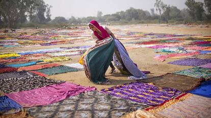 Un niño recoge unos tejidos después de secarse al sol en India.