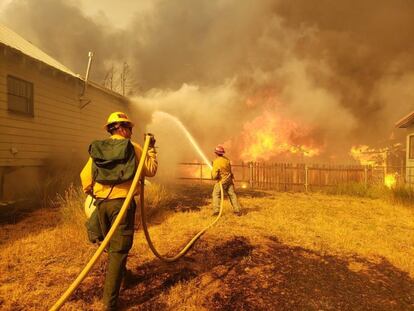 El incendio, bautizado como "Dixie" por las autoridades, ya lleva arrasadas más de 110.000 hectáreas y ha forzado el desalojo de los en torno a 1.000 vecinos de Greenville, en la ladera de la Sierra Nevada, en el noreste californiano. En la imagen, dos bomberos luchan contra las llamas en Greenville, el 5 de agosto. 

