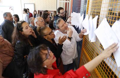 Varios ciudadanos buscan su mesa en las listas para votar en el Ministerio de Educación, en Madrid.