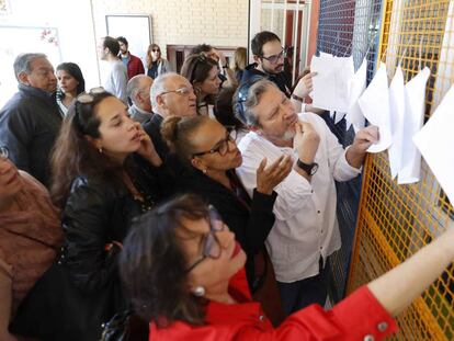 Varios ciudadanos buscan su mesa en las listas para votar en el Ministerio de Educación, en Madrid.