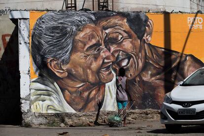 Uma mulher com carrinho de compras fala e gesticula em frente à pintura, como se estivesse conversando com o casal retratado.