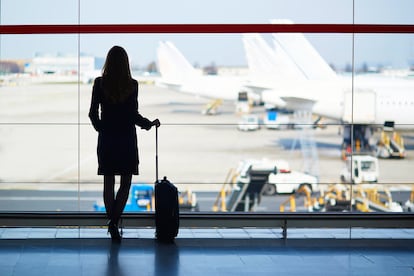 Viajera de negocios frente a una ventana en un aeropuerto.