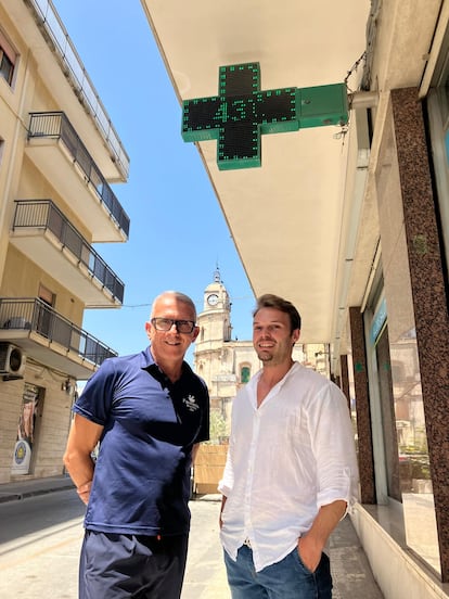 De izquierda a derecha, Elio Morale y Biagio Cantone, debajo del termómetro de su farmacia en Floridia, Sicilia, el municipio donde en 2021 se registró el récord europeo de calor, 48,8 grados (medido en una estación meteorológica).