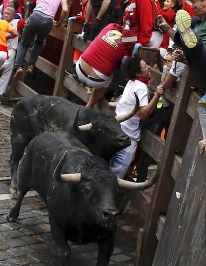 Un mozo sufre una cogida en la curva de Mercaderes durante el quinto encierro.