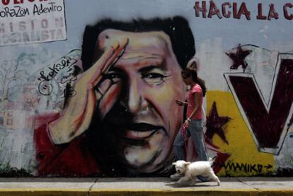Una mujer pasea en Caracas ante un mural con la imagen de Hugo Chávez.