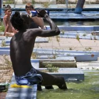 Una persona se refresca en una fuente céntrica de Sevilla.